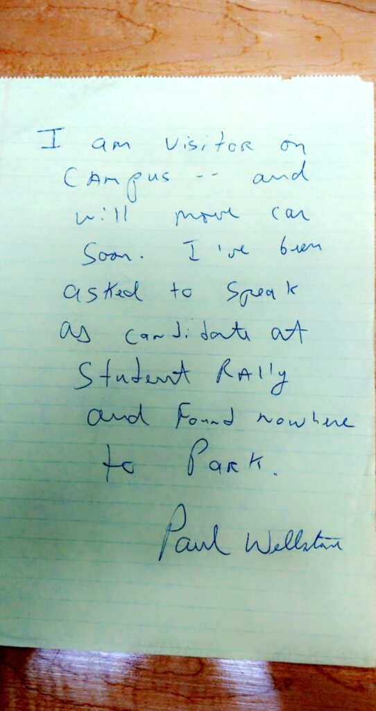 A note, signed by Paul Wellstone, handwritten: "I am visitor on campus -- and will move car soon. I've been asked to speak as candidate at student rally and found nowhere to park. --Paul Wellstone"